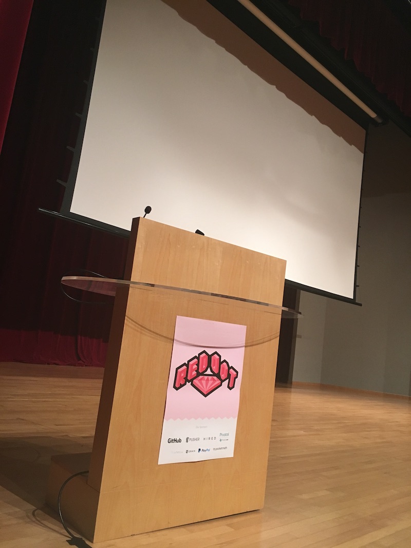 RedDotRubyConf 2016 poster on the speaker table on stage