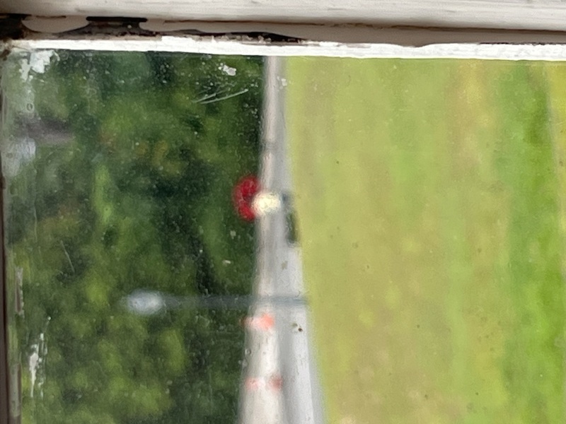 Blurred window view of a lady holding a red umbrella, in Botanical Art Gallery, Singapore